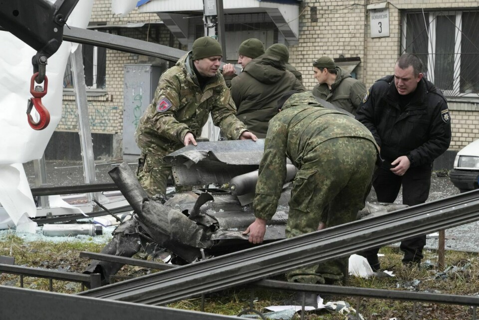 Ukrainske arbeidere jobber for å fjerne restene av en rakett etter russisk beskytning i Kyiv torsdag morgen. Foto: Efrem Lukatsky / AP / NTB