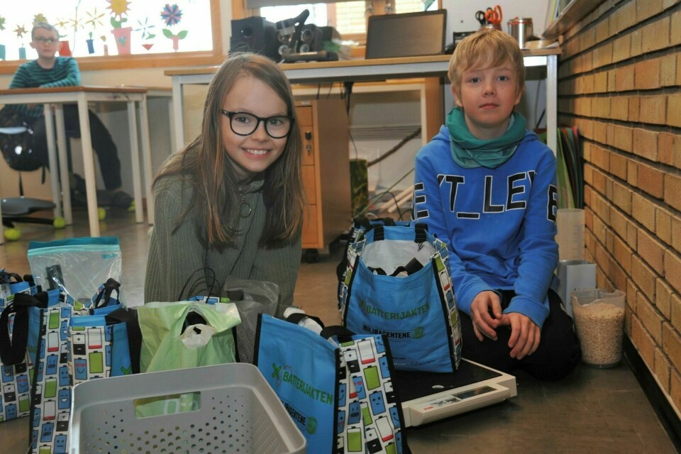MÅLER: Her måler Alva og Theodor posene med batteri som klassene har samlet inn. Denne posen veier 11,6 kilogram. Foto: Marius Mikalsen
