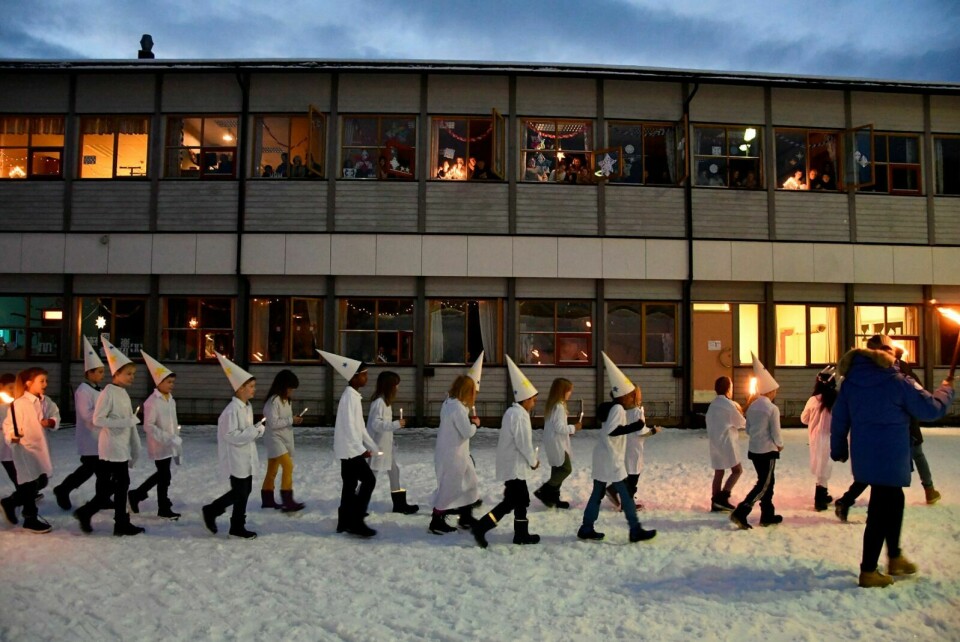 PUBLIKUM: Mange skuelystne satt i ved sine vinduer og beskuet luciatoget som gikk rundt skolen. Foto: Torbjørn Kosmo
