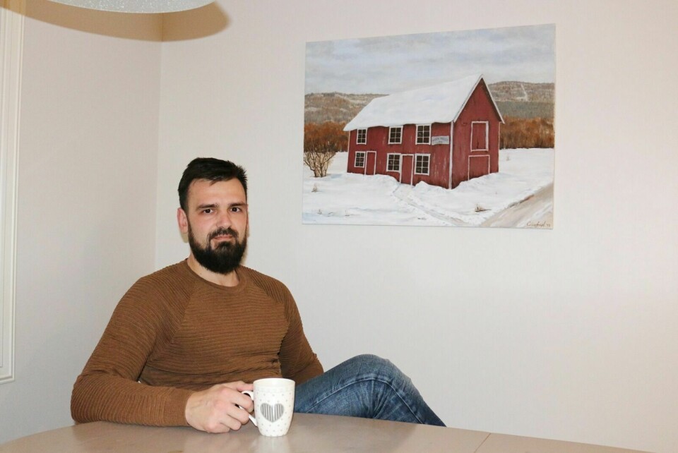 MOEN MØLLE: Stefan Stojanovic med sitt eget maleri av Moen Mølle hengende bak seg på veggen hjemme på Moen. Foto: Fredrikke Fjellberg Moldenæs
