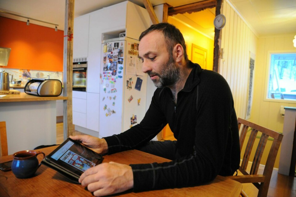 FORSIDER: Luc Soubeyrat sitter ved kjøkkenbordet i Målselv og ser på karikaturer på forsidene av Charlie Hebdo. Herfra har han fulgt terrorhandlingene som har funnet sted i hjemlandet den siste uka. Foto: Maiken Kiil Bartholdsen