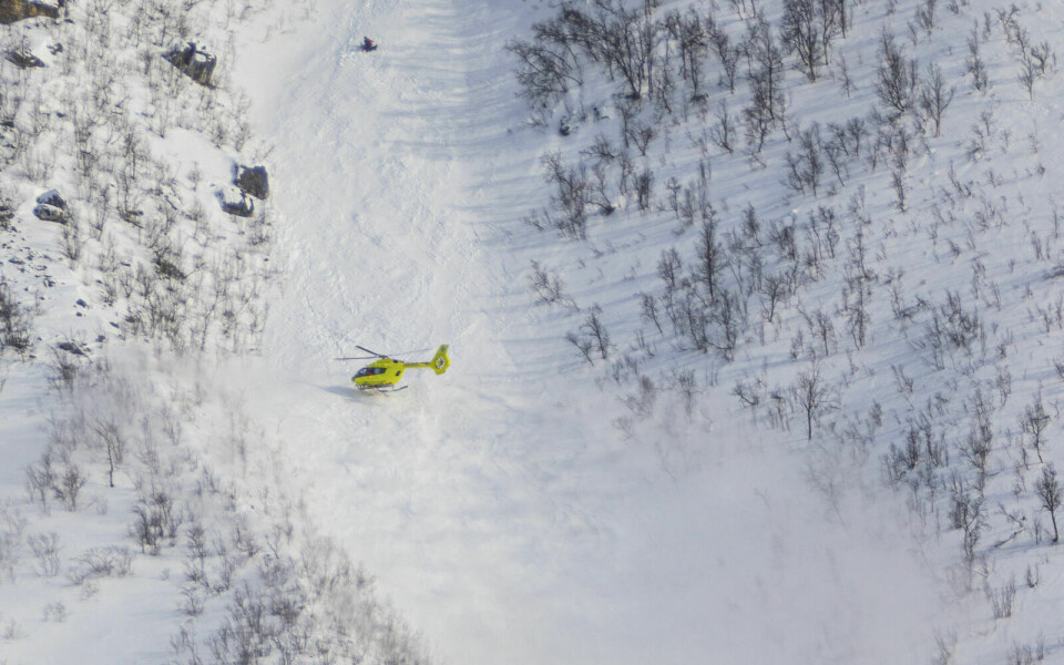 PÅ STEDET: Et ambulansehelikopter over snøskredet, som gikk på vestsiden av Blåruttinden. Foto: Maja Meyer/ Forsvaret / NTB